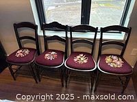 front view of four dark wood chairs with floral needlepoint seats