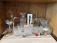 shelf view showing decanters, glasses, martini glasses, picks, stirrers, bar spoon and wine filter funnel