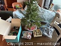 Overall lot: tree, box of ornaments, lights, tree skirt visible on table