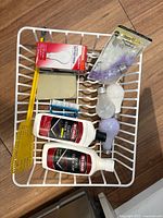 Basket with cleaners, bulbs, fly swatter, scrub pad, brush in dish rack