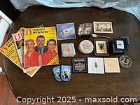 Group shot of magazines, coasters, dish, spoon, patches and DVD on table