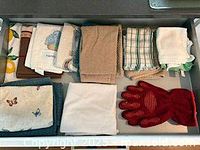 Drawer showing folded dish towels and red oven mitt