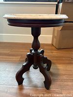 Side view showing marble top and wooden pedestal three-leg base