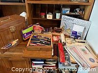 Overview of assorted office supplies on wooden surface, pens, stationery, calendars visible