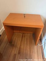Front angled view of small wood desk showing open knee space and power cord