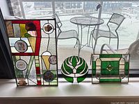 Three stained glass panels on windowsill showing overall lot