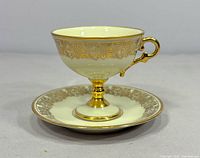 Side view of footed cup on saucer showing gilt floral band