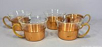 Five glass cups in copper holders, cane handles visible
