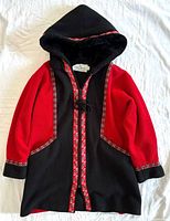Front view of black and red hooded jacket laid flat