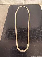 Full view of sterling silver flat snake chain necklace laid flat showing length and clasp