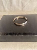 Sterling silver bangle resting on box, full view