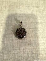 Front view of sterling silver garnet and marcasite pendant on fabric background