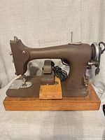 Full view of Seamstress Rotary electric sewing machine on wood base with foot pedal and cord
