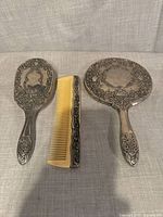 Front view of brush back, comb spine, and mirror back showing ornate engraving