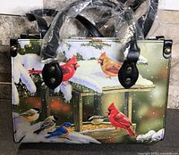 Front of handbag showing winter bird scene print, black trim and short handles