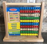 Front view of sealed Melissa & Doug wooden abacus displaying colorful beads and packaging insert