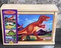 Front of boxed wooden puzzle set showing dinosaur image and age 3+ logo