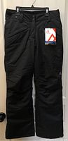 Full frontal view of black Ripzone snow pants hanging with tags attached