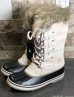 Left side view of both boots showing suede upper, faux fur cuff, rubber shell toe, and tag attached