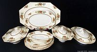 Front view of entire dishware set with platters, covered bowls, plates stacked