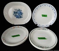 Group shot showing platter, single blue garland plate, stack of four peach floral plates, stack of five green vine plates