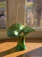 Iridescent green glass basket front view with clear applied handle