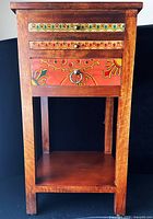 Front view of Suzani games table showing painted drawer fronts and lower shelf