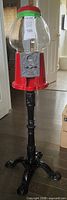 Full view of red gumball machine with glass globe on black cast metal stand