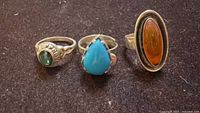 Front view of three sterling silver rings with green, turquoise, and orange stones