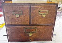 Front view showing three drawers and brass hardware