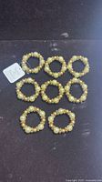 Eight gold and cream beaded napkin rings arranged in rows