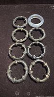 Group of seven bronze-tone napkin rings and one clear ring