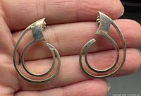 Front view of both sterling silver abstract earrings resting on fingertips