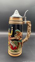 Full view of ceramic beer stein showing relief tavern scene and branch handle