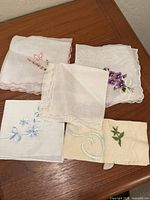Five embroidered and lace handkerchiefs laid out