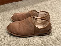 Side view of brown suede UGG slippers showing shearling lining and logo