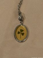 Close-up of pendant showing four-leaf clover inside oval silver-tone frame