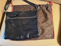 Front view of black leather Coach bag on brown dustbag