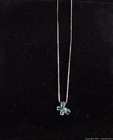 Full view of necklace with flower pendant against black background