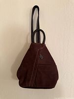 Front view of brown suede backpack purse hanging, shows triangular shape and front pocket