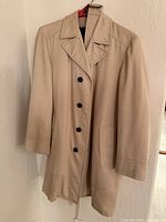 Full view of tan overcoat on hanger
