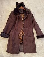 Front view of brown hooded faux suede long coat showing buttons and leopard scarf
