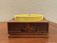 Front view showing walnut base with laser-engraved sailboat and yellow glass insert seated
