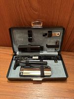 Open case showing grey felt interior and six grooming accessories secured with straps