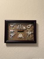 Full view of framed shadow box showing ship model and knots