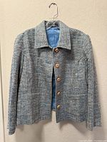 Front view of tweed blazer on hanger showing buttons, collar, lining