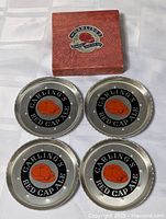Four coasters displayed with box lid showing logo