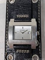 Close-up of Fossil watch face on leather cuff strap