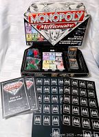 Closed Monopoly Millionaire box, open box with contents, rulebooks and punchboard of Millionaire cards
