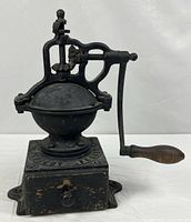 Full view of cast iron Peugeot coffee grinder showing crank, base and drawer